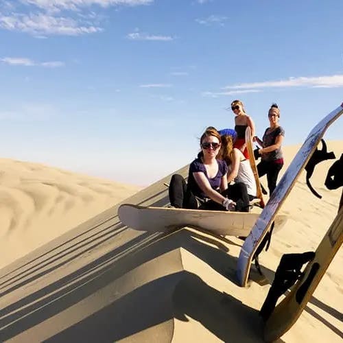 group sandboarding on dunes