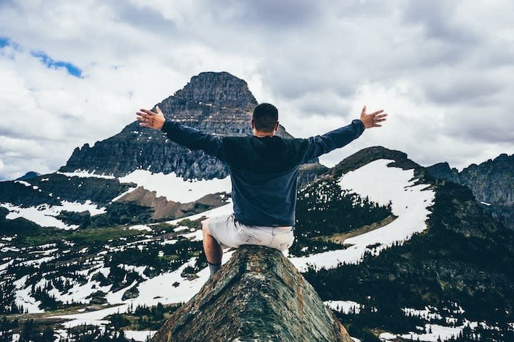 Man sitting on mountain, remote work travel tips