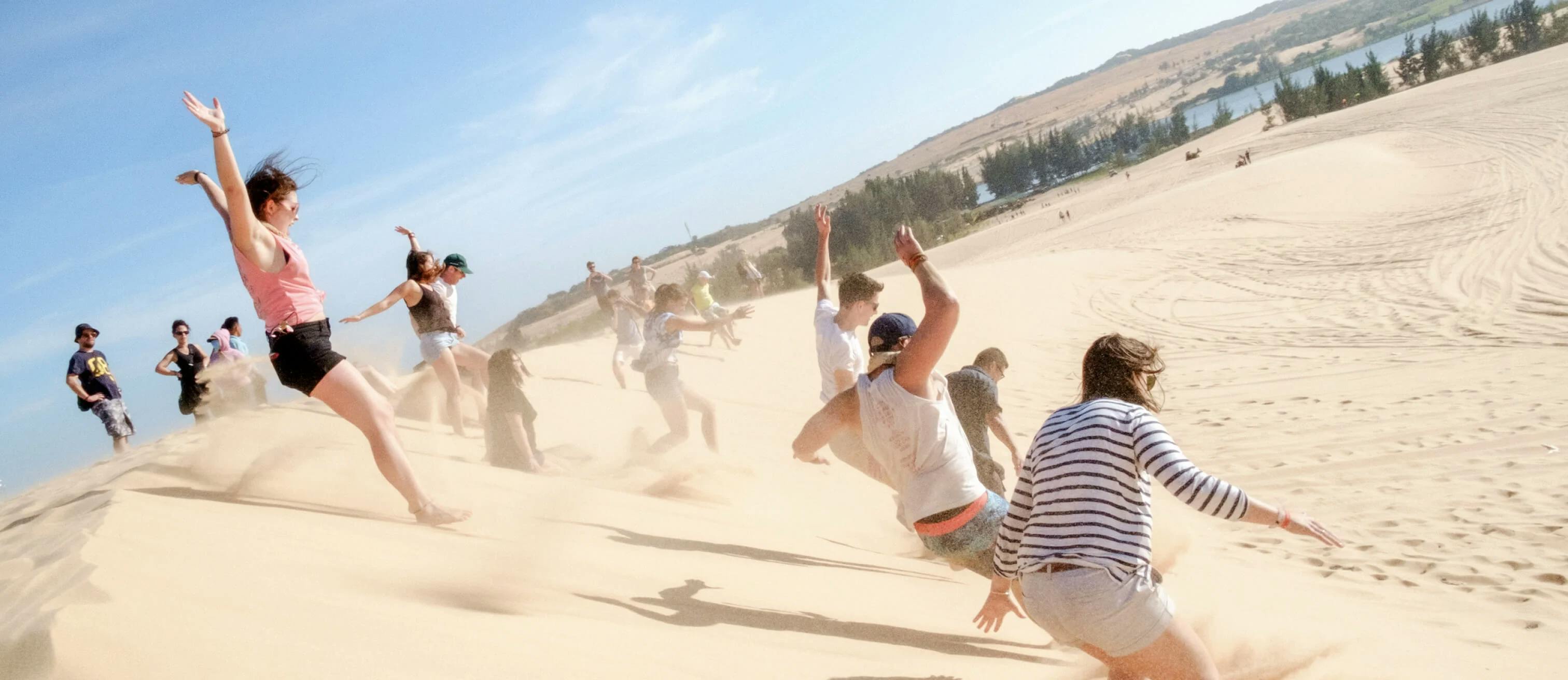 people jumping in sand dunes